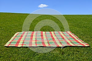 An empty picnic blanket on green grass