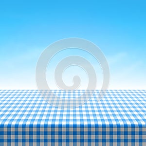 Empty picnic table covered with blue checkered tablecloth photo