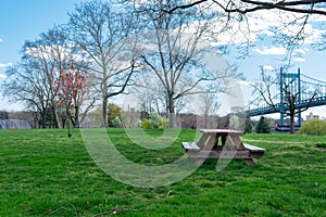 Empty Picnic Table and a Green Lawn at Randalls and Wards Islands during Spring with a view of the Triborough Bridge