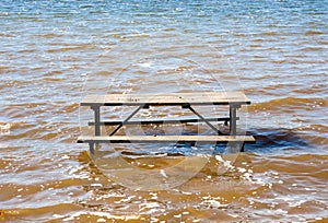 Empty picnic table in muddy brown water