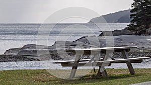 Empty picnic table in park with ocean background.