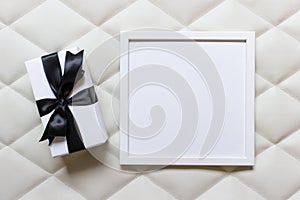 Empty picture frame with a present with black bow on white tufting fabric cloth