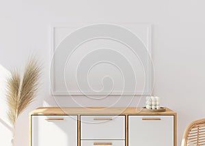 Empty picture frame on white wall in modern living room. Mock up interior in scandinavian, boho style. Close up view