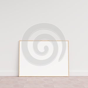 Empty picture frame on wooden floor leaning against wall. Blank poster frame standing on wooden floor. Blank poster frame mockup.