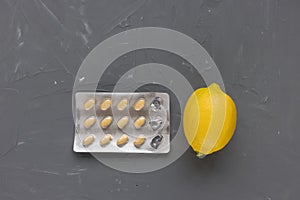 Empty pill blister and lemon on gray background, supplement of vitamin C concept