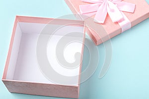 Empty pink gift box and decorations on white wooden table on mint colored paper background