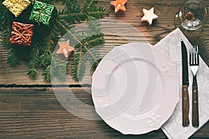 Empty pink plate, glass, cutlery, decorations on wooden background. Christmas table setting captured from above. Top view, flat