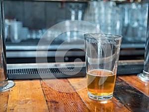 Almost empty pint glass of beer sitting on countertop for last c