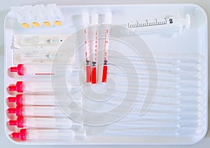 Empty pipettes, droppers, vails and syringe on white tray on laboratory worktop photo