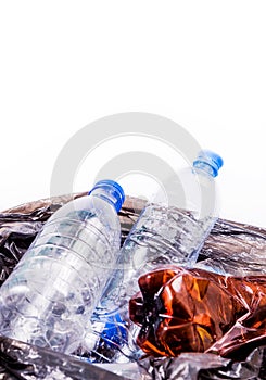 Empty plastic bottle in a black trash bag on a white background