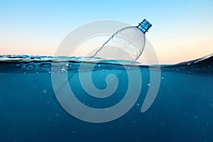 Empty plastic bottle floats in water. Ocean pollution concept. Global warming. View under water.