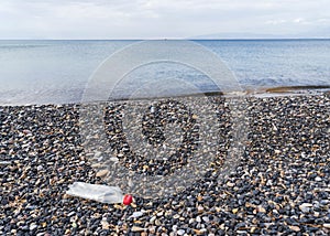 Empty plastic bottle on a pebble beach, the concept of plastic pollution.
