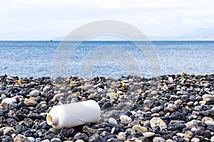 Empty plastic bottle on a pebble beach, the concept of plastic pollution.