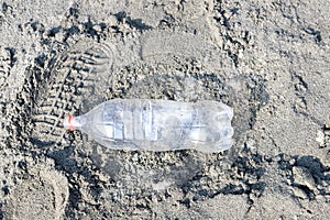 Empty plastic bottle trash laying on a sandy beach. Plastic pollution concept