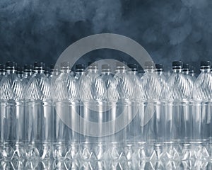 Empty plastic bottles on black background with smoke, pollution concept