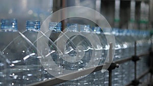 Empty plastic bottles with a volume of 5 liters move along the conveyor in the workshop of the mineral water bottling plant. Produ