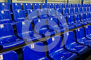 Empty plastic chairs in the stands of the stadium. Many empty seats for spectators in the stands. Empty plastic chairs seats for