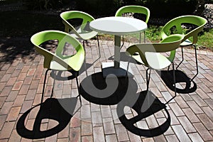 Empty plastic chairs and table in green at a cafe