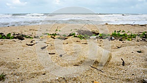 An empty plastic cup on the sandy beach at Batu Burok Beach in Kuala Terengganu