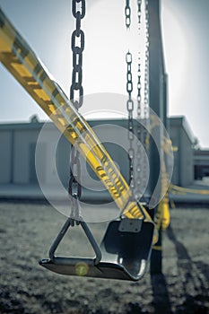 Empty plastic swings on playground with caution tape, selective focus