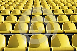 Empty plastic yellow seats at stadium, open door sports arena.