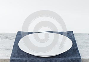 Empty plate on tablecloth on wooden table over grunge background