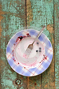 Empty plate with blueberry pie remains on turquoise background
