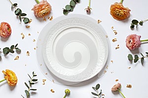 Empty plate concept flat lay with floral decorations on the white backdround. Top view