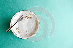 Empty plate with crumbs after eating on a green background. The concept of the end of the holiday or celebration. Nearby