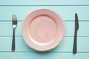 Empty plate and cutlery on wodden background, colorful pink and turquoise colors