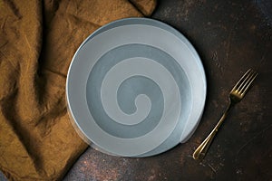 Empty plate on a dark background. Empty gray ceramic plate with a knife and fork for food and dinner on a dark beautiful