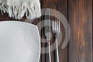 Empty plate, fork and knife on dark wood background
