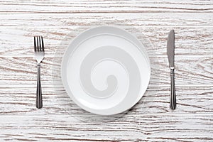 Empty plate fork knife silverware white wooden table background