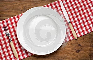 Empty plate with fork and knife on tablecloth over