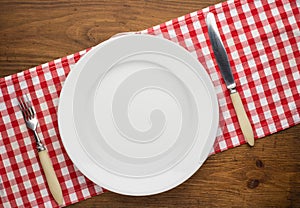 Empty plate with fork and knife on tablecloth over