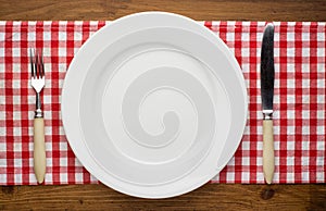 Empty plate with fork and knife on tablecloth over