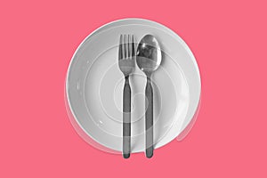 Empty plate fork spoon on a color background