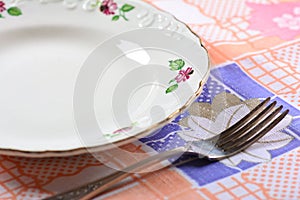 Empty plate and fork on table
