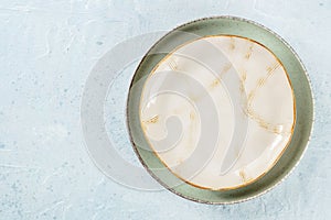 An empty plate with a gold rim, shot from above on a slate background