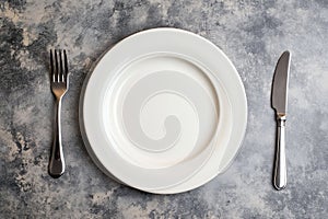 Empty plate, knife and fork on concrete background. Top view