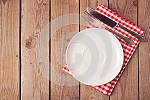 Empty plate with knife and fork on wooden rustic table. View from above.