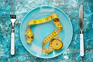 Empty plate with measure tape, knife and fork. Diet food concept