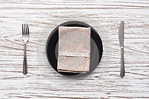 Empty plate napkin fork knife silverware white wooden table background