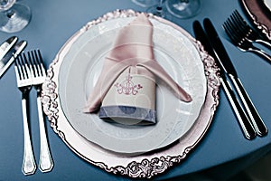 Empty plate with napkin, forks and knives on light blue tableclothes. Beautiful table setting on blue background. Festive table se