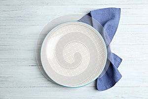 Empty plate and napkin on white table, flat lay