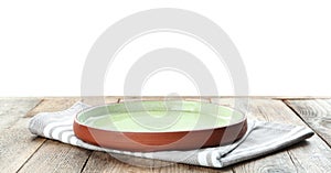 Empty plate and napkin on wooden table against background