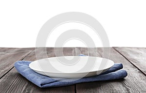 Empty plate and napkin on wooden table against background