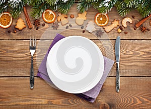 Empty plate with silverware over christmas wooden background