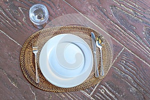 Empty plate with spoon, knife and fork on wooden natural backgro