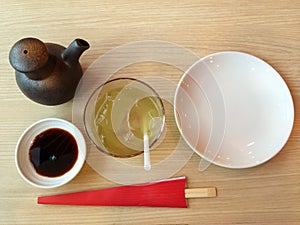 Empty plate, sushi chopsticks , soy sauce and ice green tea on wooden table